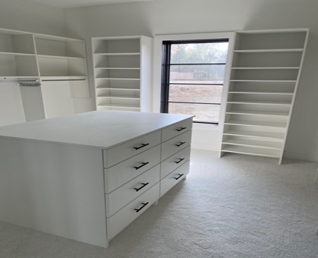 new, white custom closet with a drawer island